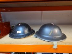 Two similar World War II era Civil defence metal helmets with liners