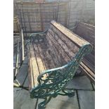 An old cast iron garden bench having decorative ends with wooden slatted seat and back