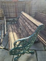 An old cast iron garden bench having decorative ends with wooden slatted seat and back