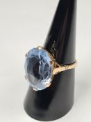 9ct yellow gold cocktail ring set with large oval pale blue faceted paste stone in 6 claw mount, 5.5