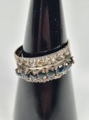 Yellow metal dress ring with central row of round cut sapphires, central to two rows of clear stones