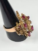An attractive 14K yellow gold ring with large raised textured panel set round cut diamonds and 4 ova