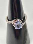 9ct white gold dress ring with central oval cut Tanzanite and Zircon inset into cross over design sh