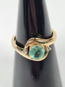 9ct yellow gold dress ring with central round cut emerald in circular cross over design mount, two s