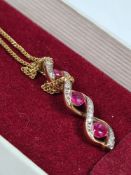 9ct yellow gold fine neckchain hung with pendant of twisted form inset 3 graduated round cut rubies