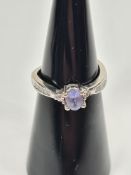 9ct white gold contemporary dress ring with central oval tanzanite and chanel set diamond to shoulde