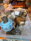 A box of mixed china and glassware including oil lamps and a bottle of champagne
