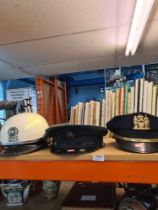 An Ulster Constabulary Police hat and two others including a U.S.A. motorcycle helmet