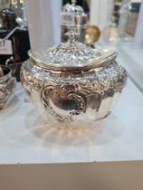 An ornate Edwardian silver caddy having embossed scroll details, and on the hinged lid, foliate swag