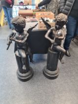 A pair of reproduction bronzed figures of Cherubs, playing flute, seated on columns, 103cm