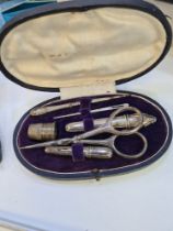A cased silver sewing set marked 800, comprising scissors, stiletto, bodkin, needle cases, and a thi