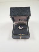 18K white gold dress ring with central mixed cut blue sapphire framed with 12 round brilliant cut di