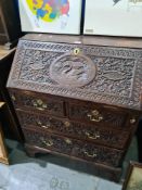 An antique oak Bureau probably early 19th Century, having all over carved decoration, 76cm