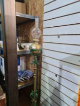 An early 20th Century oil lamp on adjustable stand with scroll decoration and a reproduction stick s