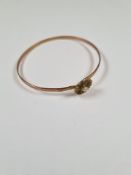 Unmarked yellow gold bangle with hook clasp below flowerhead, inset with seed pearls, 6cm diameter,
