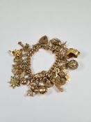 9ct yellow gold charm bracelet hung with approx 28 charms, one being 18ct, other charms include dolp
