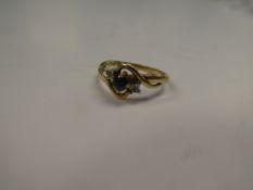 9ct yellow gold crossover design ring with central sapphire and two small diamond chips, marked 375,