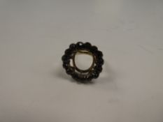 Unmarked yellow metal ring with large raised halo inset garnets, possibly originally mourning ring,