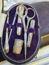 A cased silver sewing set marked 800, comprising scissors, stiletto, bodkin, needle cases, and a thi