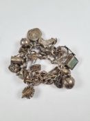 Silver charm bracelet hung with a large number of charms including hedgehog, key, cart, duck, gnome,
