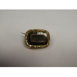 Unmarked yellow metal mourning brooch, with central panel containing lock of hair, surrounded black