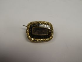 Unmarked yellow metal mourning brooch, with central panel containing lock of hair, surrounded black