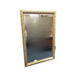 A large contemporary mirror in leaf moulded gilt cushion shaped frame. (46.25in x 31in)