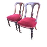 A pair of late Victorian mahogany dining chairs with shaped moulded backs framing pierced splats,