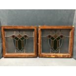 A pair of leaded stained glass windows with coloured shield shaped decoration in moulded wood