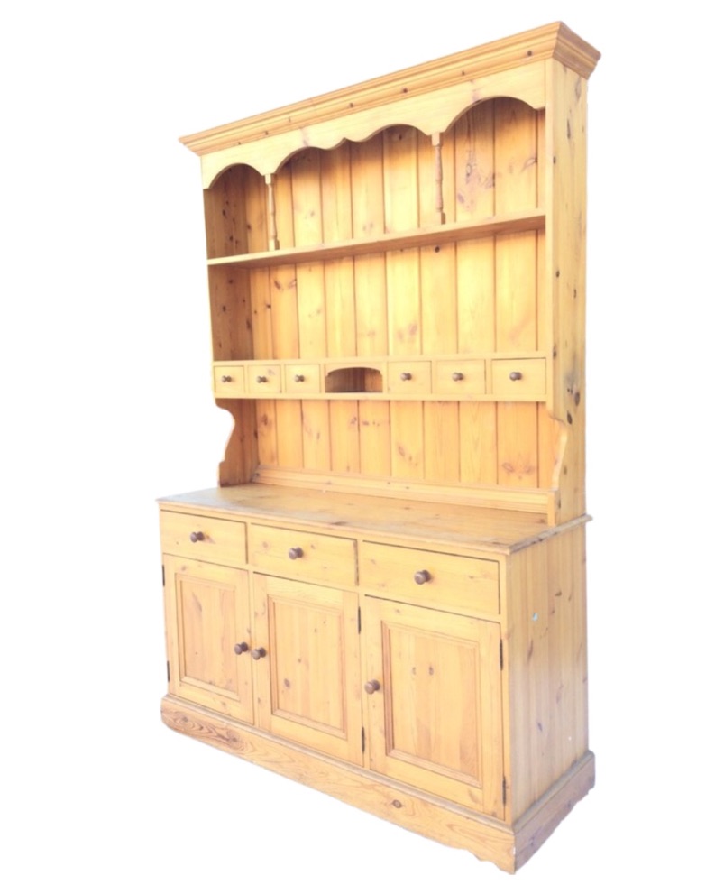 A pine dresser with moulded cornice to delft rack having shaped apron supported on spindles above an