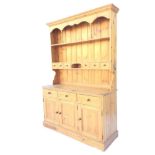 A pine dresser with moulded cornice to delft rack having shaped apron supported on spindles above an