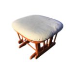 A rectangular Canadian rocking stool by Dutailier, with rounded cushion seat on platform supported