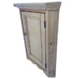 A hanging pine corner cabinet with moulded cornice above a knobbed panelled door and shaped