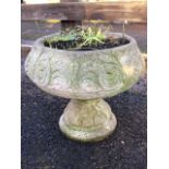 A composition stone garden urn with tulip shaped basin cast with scrolling on waisted conforming