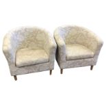 A pair of contemporary tub armchairs of horseshoe shape with loose cushions, raised on turned
