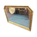 A rectangular gilt framed overmantle mirror, the plate in foliate moulded frame with canted corners.