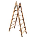 A set of pine decorators ladders with two-way steps, each side with seven tapering ribbed treads. (