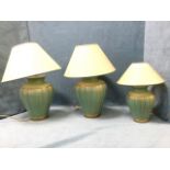 A suite of three vase tablelamps with parchment style shades, the green glazed fluted pots with