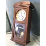 A 30s oak cased Vienna style wallclock with arched top above a moulded framed door, enclosing a