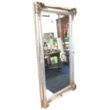 A large contemporary bevelled mirror with rectangular plate in silvered embossed foliate scrolled