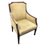 An Edwardian mahogany upholstered armchair, with downswept arms above a sprung seat, raised on