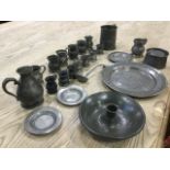 A collection of early pewter including measures, an inkwell, tankards, a jug, a mask decorated