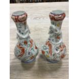 A pair of Japanese juglet vases with lizard entwined necks, painted with polychrome birds and