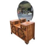 An art deco walnut dressing table with cloud shaped bevelled mirror above cabinet with two short and