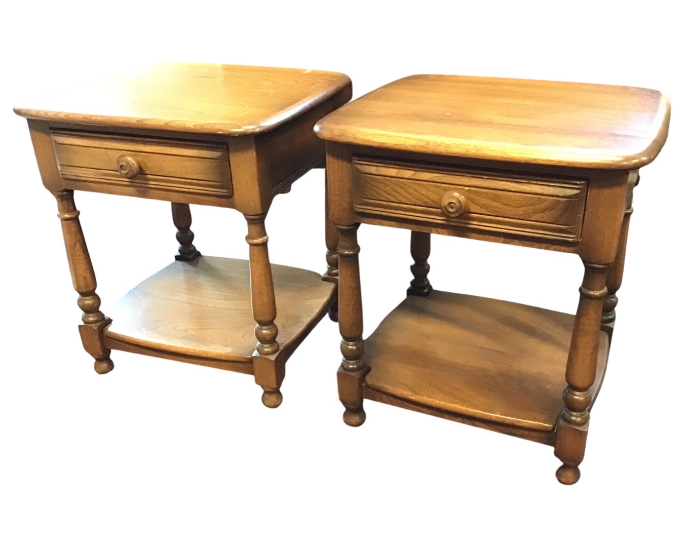 A pair of Ercol elm bedside tables with square rounded tops above ribbed frieze drawers, raised on