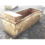 A rectangular galvanised trough with tubular rim, the end with compartment for water supply. (49in x