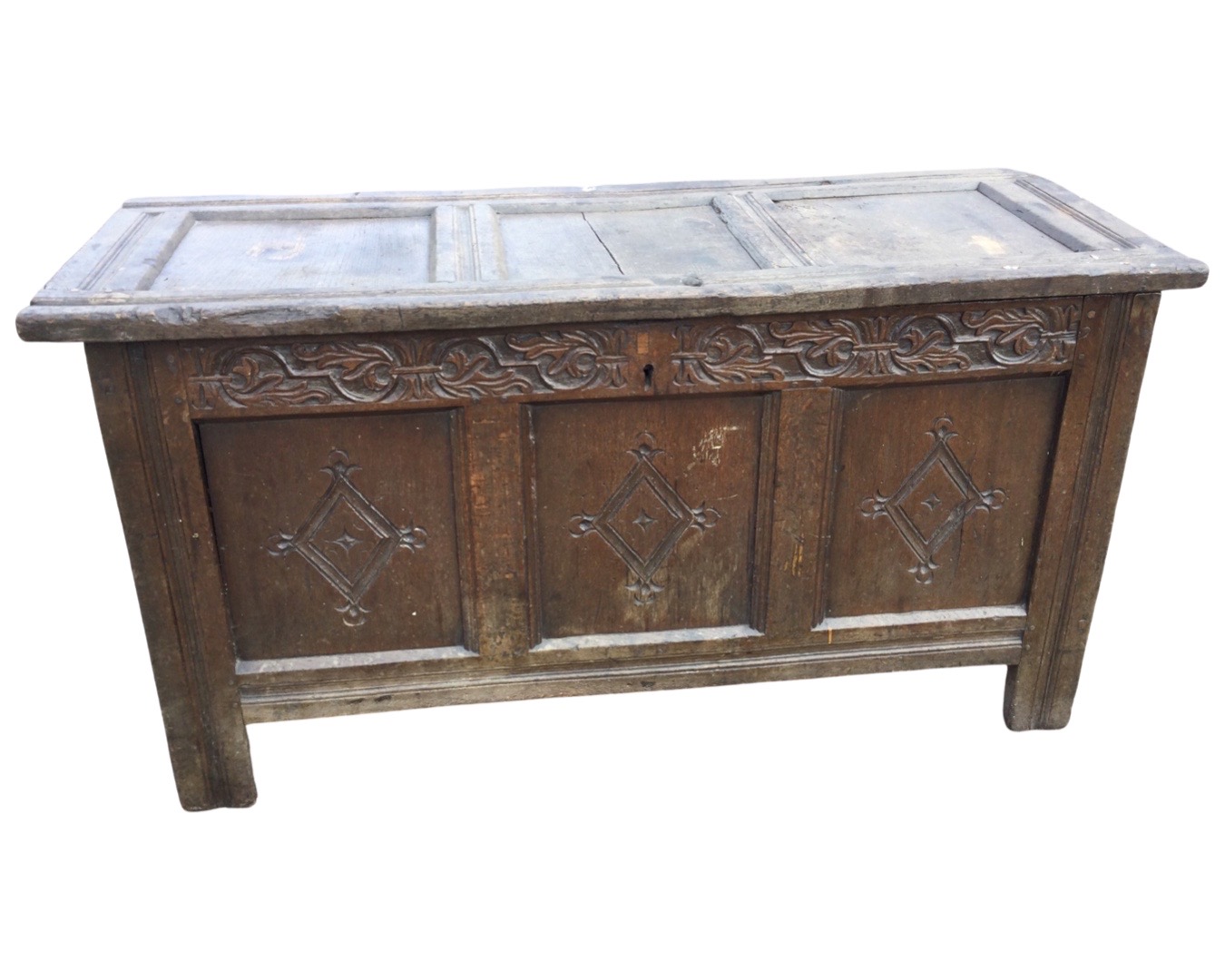 An antique oak coffer with three panels to hinged lid, the front with foliate scroll carved blind