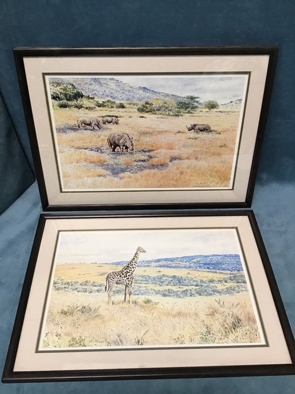 Jeff Huntly, a pair of coloured prints, African landscapes with rhinos and girafffe, signed in print