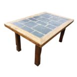 A chunky rectangular pine table with slate tiled panel to top, raised on square tapering column