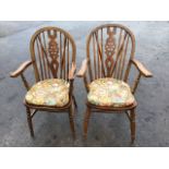 A pair of oak wheelback elbow chairs, the hooped backs on spindles framing pierced splats, the